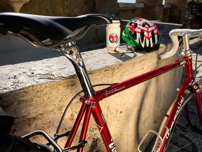 Tommasini Sintesi red steel road bike resting on a stone terrace in the Tuscan sun