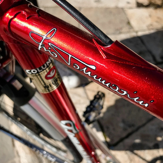 Close-up of the Tommasini script signature on a metallic red Sintesi steel frame with Columbus tubing decal