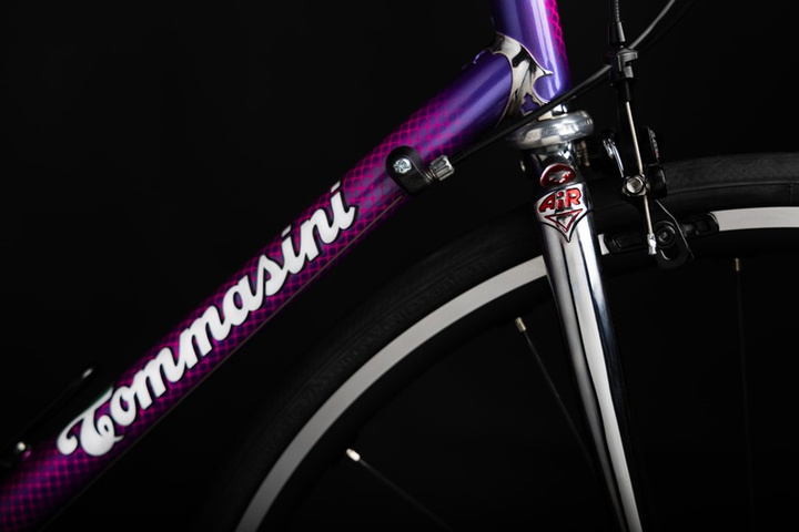 Close-up of the Tommasini script logo on a purple steel head tube